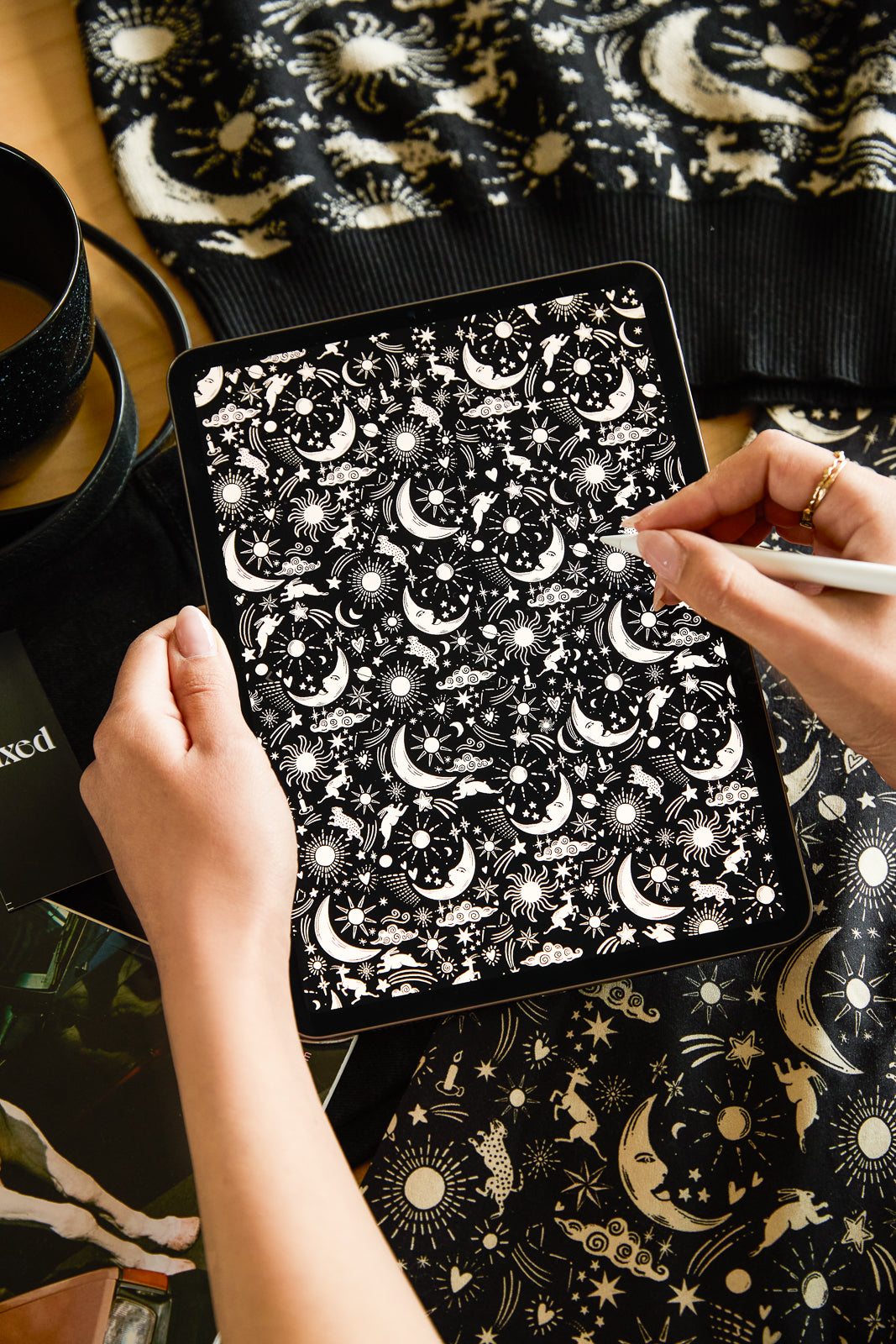 Person holding a tablet with a star and moon pattern on a surface with similar design