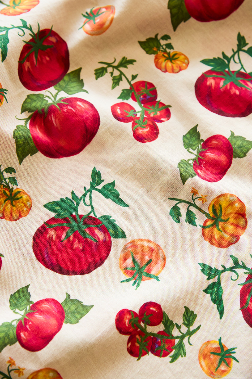 Pattern of tomatoes and green leaves on a beige background