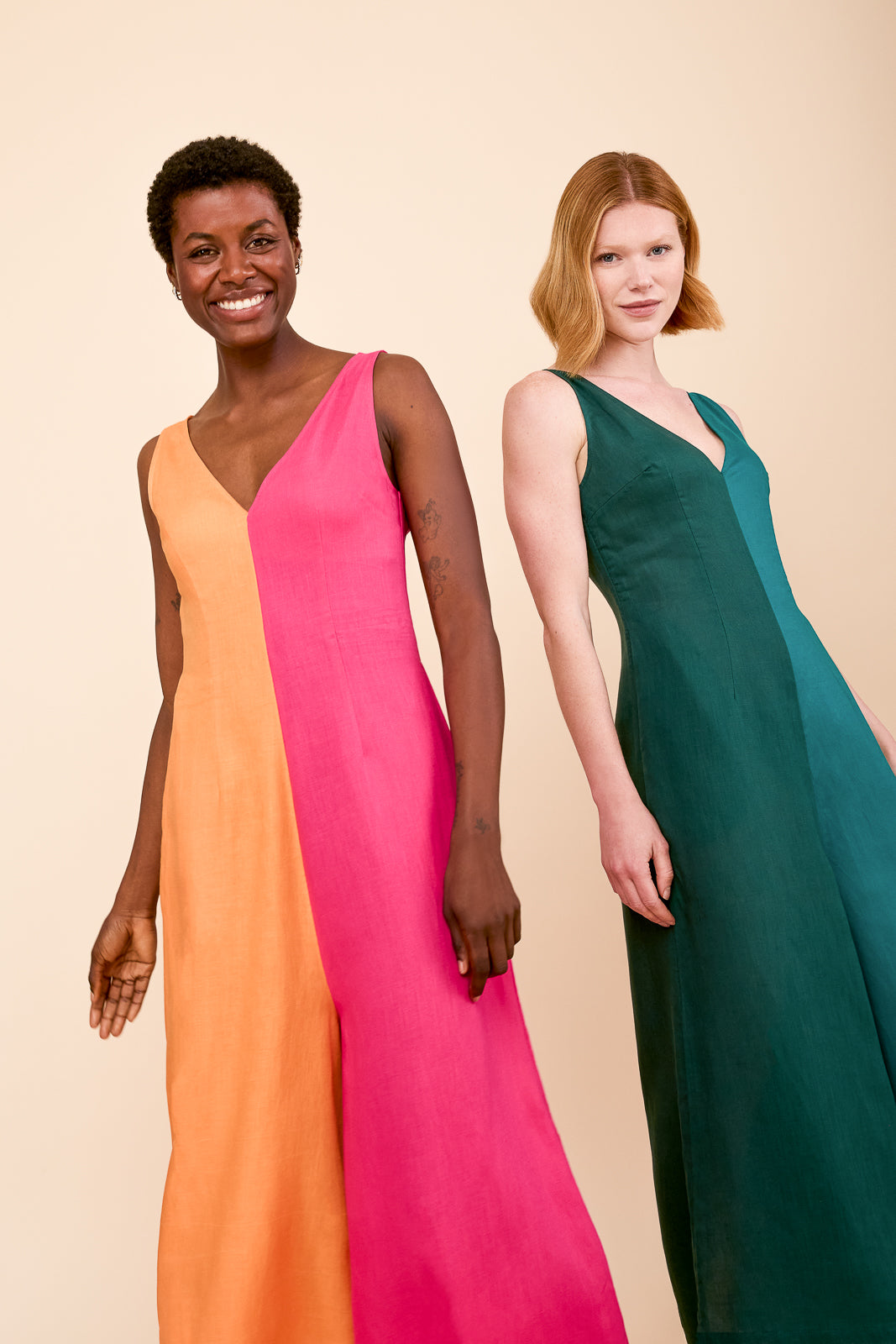 Two women wearing color block jumpsuits on a beige background