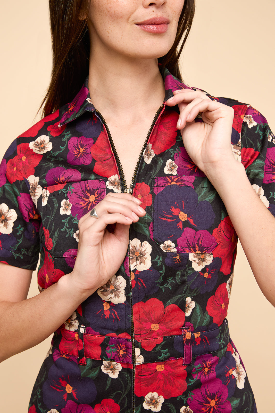Close up view of Quincy jumpsuit in pansy. Red and blue floral pattern