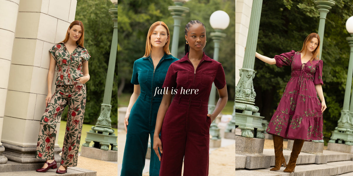 A three-panel collage showing three women modeling coordinated outfits outdoors near stone columns and greenery. The left panel shows a woman in a floral short-sleeve jumpsuit; the center panel shows two women in solid teal and burgundy jumpsuits with the text 'fall is here' across them; the right panel shows a woman in a burgundy floral dress with brown boots.